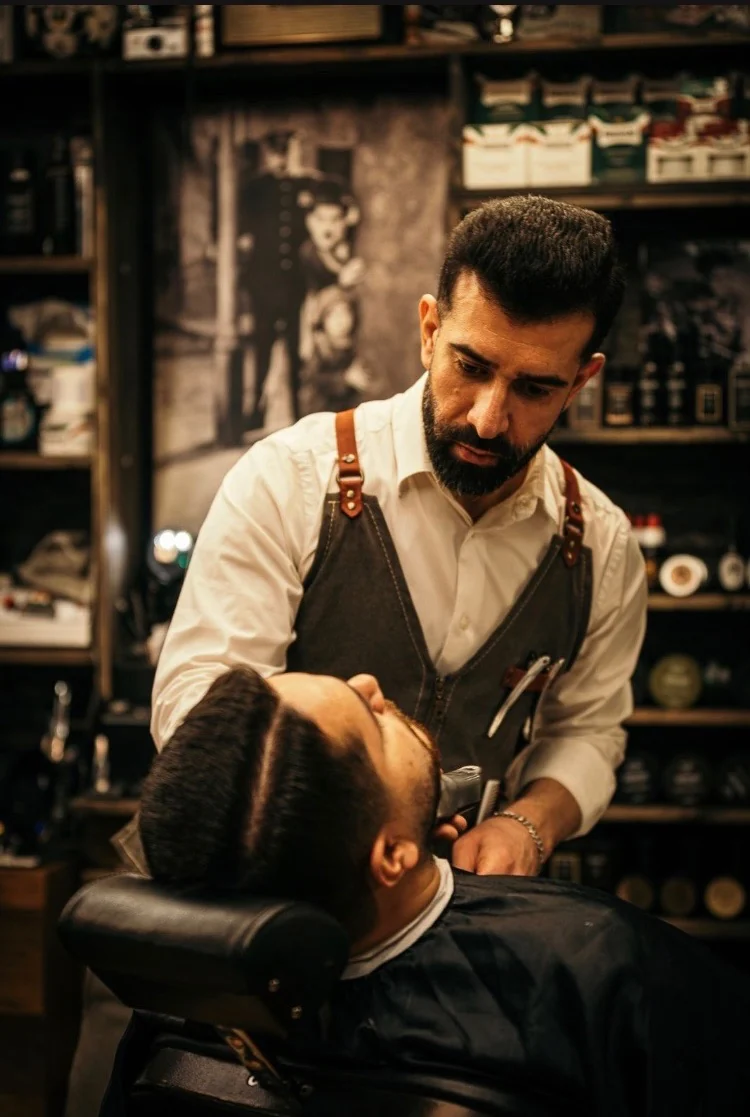 Hardi vid barberarstolen framför salongens Chaplin-affisch