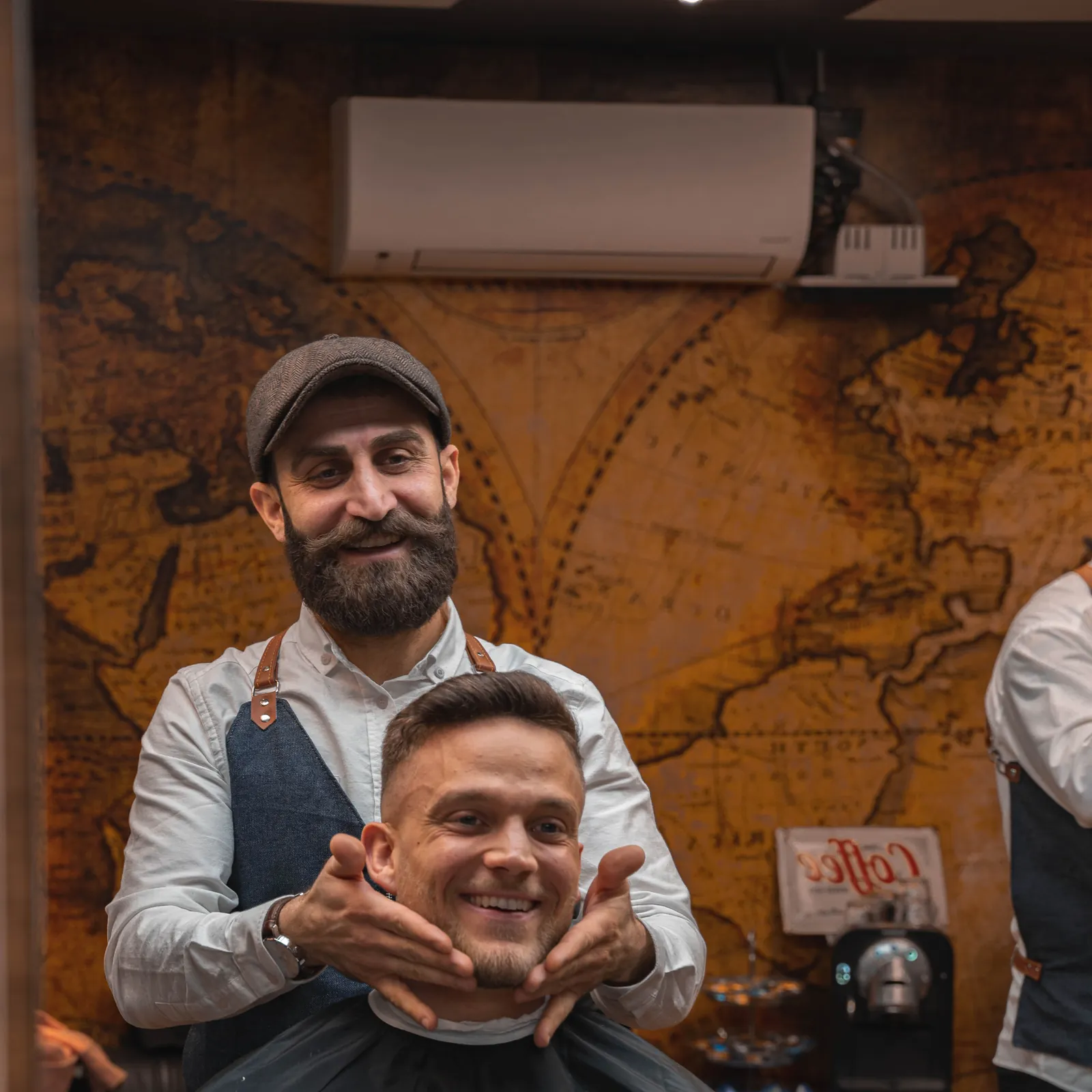 Dilman skrattar tillsammans med en nöjd kund i barberarstolen